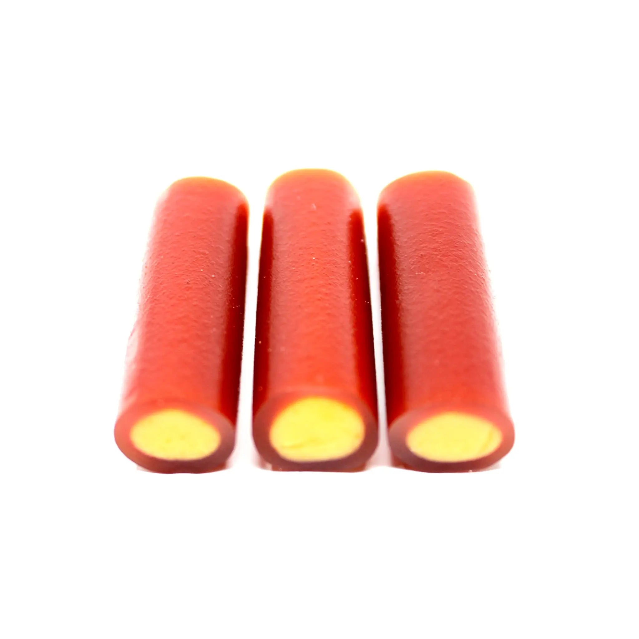 Three pieces of Swedish candy looking like pipes in dark orange and a yellow inside.